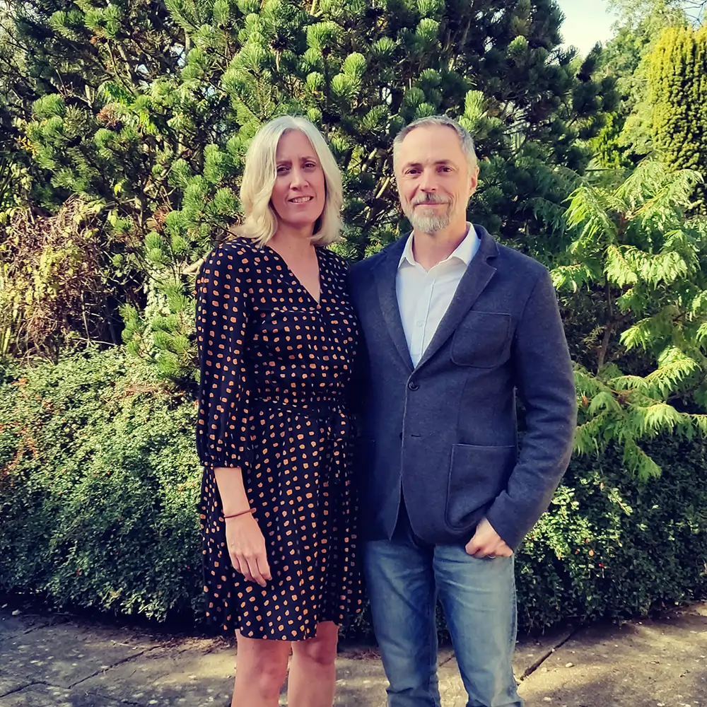 A recent photo of my wife and I in colour, standing in front of a bush