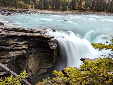 A photograph of a waterfall, the water is flowing over a rocky ledge, a long exposure has been used, so the water has a smooth appearance.