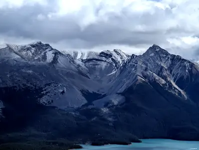 A photograph of some distant snow-capped mountains, between two of the mountain peaks is a valley which carves out a circular shape.